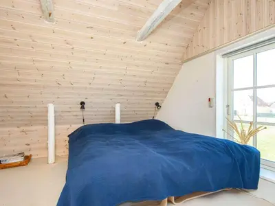 a bedroom with a blue bed in a wooden wall at 10 person holiday home in Harboøre-By Traum in Harboør