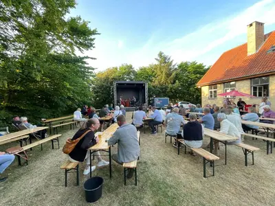 a crowd of people sitting at tables watching a stage at Room 8 - Hawkraft kulturhotel in Vestervig