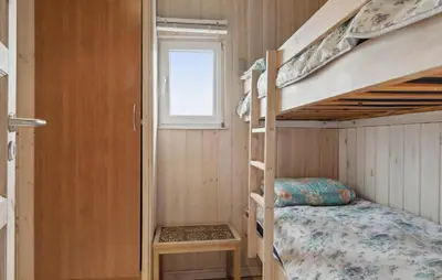a small bedroom with bunk beds and a window at Stunning Home In Løkken With Sauna in Løkken