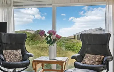 two chairs in front of a window with a vase of flowers at Stunning Home In Løkken With Sauna in Løkken