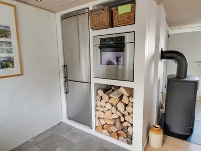 a kitchen with a stove and a bunch of logs at Holiday Home Alkmar - 75m from the sea by Interhome in Thisted