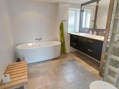 a bathroom with a tub and two sinks and a toilet at Holiday Home Alkmar - 75m from the sea by Interhome in Thisted