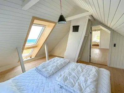 a bedroom with a large white bed in a attic at Holiday Home Alkmar - 75m from the sea by Interhome in Thisted