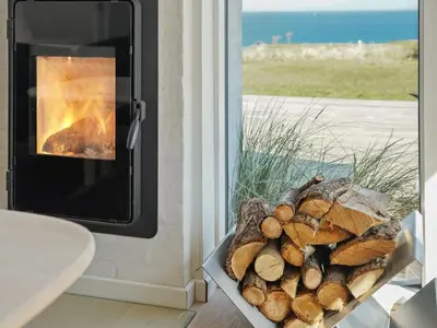 a pile of logs in front of a fireplace at Holiday Home Alkmar - 75m from the sea by Interhome in Thisted