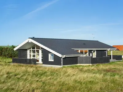 a house with a black roof on a field at Holiday Home Appollina - 400m from the sea by Interhome in Torsted