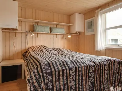 a bedroom with a bed in a room with a window at Holiday Home Eunike - 220m from the sea by Interhome in Løkken