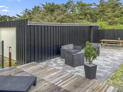 a patio with a black fence and a table and a bench at Holiday Home Telma - 200m from the sea by Interhome in Blokhus