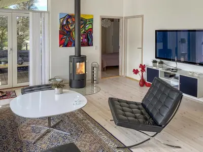 a living room with a fireplace and a table and chairs at Holiday Home Telma - 200m from the sea by Interhome in Blokhus