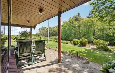 a patio with two chairs under a wooden pergola at Nice Home In Bækmarksbro With Wifi in Bækmarksbro