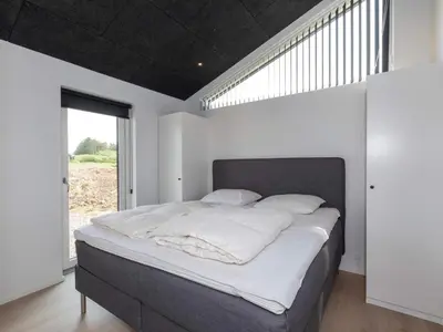 a large bed in a room with a large window at 10 person holiday home in Saltum-By Traum in Saltum