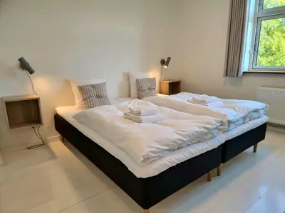 a large white bed in a room with a window at Skovsgård Hotel in Brovst