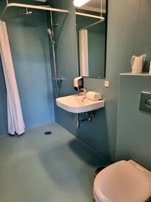 a bathroom with a sink and a toilet and a mirror at Skovsgård Hotel in Brovst