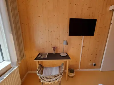 a room with a desk with a television on a wall at Skovsgård Hotel in Brovst
