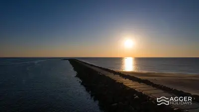 a pier stretches out into the ocean at sunset at Agger Holidays in Vestervig