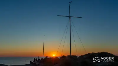 a boat on the beach with the sunset in the background at Agger Holidays in Vestervig
