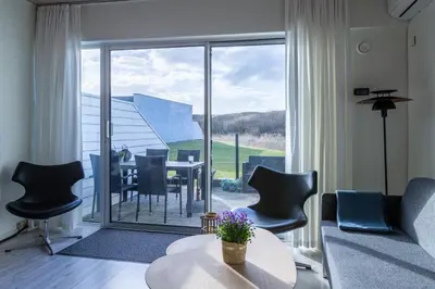 a living room with a table and chairs and a large window at Agger Holidays in Vestervig