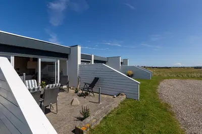 a house with chairs on the side of it at Agger Holidays in Vestervig