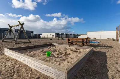 a sandbox in the sand next to a playground at Agger Holidays in Vestervig