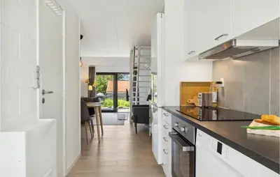 a kitchen with white cabinets and black counter tops at Nice Apartment In Blokhus With Wifi in Blokhus