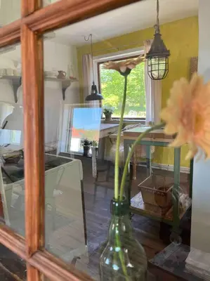 a vase with flowers in a room with a mirror at The Old Soap House - stylish and close to beach in Vang