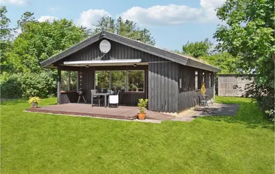 a black shed with a wooden deck in a yard at Gorgeous Home In Blokhus With Wifi in Blokhus