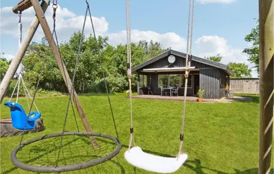 a swing in a yard with a house at Gorgeous Home In Blokhus With Wifi in Blokhus