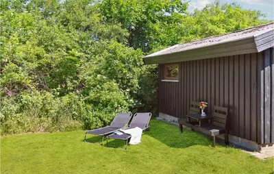 a patio with two chairs and a bench next to a building at Gorgeous Home In Blokhus With Wifi in Blokhus