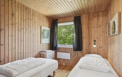 two beds in a wooden room with a window at Gorgeous Home In Blokhus With Wifi in Blokhus