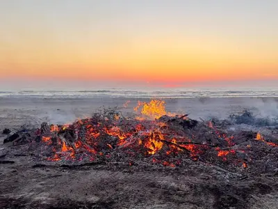 a bonfire on the beach at sunset at 6 person holiday home in Pandrup-By Traum in Pandrup