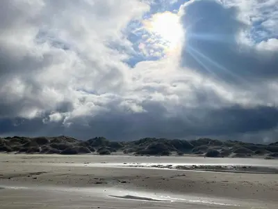 a beach with a cloudy sky and the sun at 6 person holiday home in Pandrup-By Traum in Pandrup