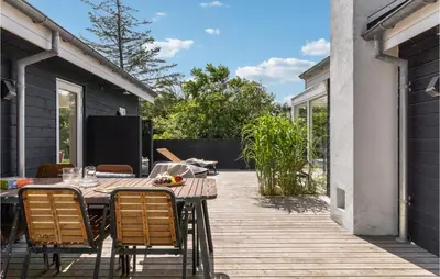 a patio with a table and chairs on a deck at Nice Home In Blokhus With Kitchen in Blokhus