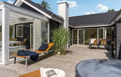 a patio with sliding glass doors and a table at Nice Home In Blokhus With Kitchen in Blokhus