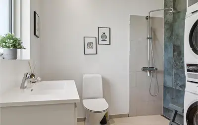 a white bathroom with a sink and a shower at Nice Home In Blokhus With Kitchen in Blokhus