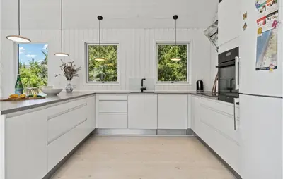 a white kitchen with white cabinets and a refrigerator at Nice Home In Blokhus With Kitchen in Blokhus