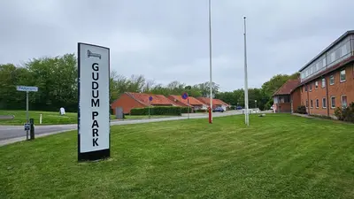 a sign in the grass in front of a building at Gudum Park in Lemvig