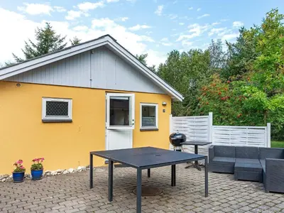 a patio with a table and a yellow house at 4 person holiday home in Hurup Thy-By Traum in Sønder Ydby