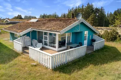 a small blue house with a deck and chairs at Skytten 5 - Environmentally Friendly Holiday Home in Hune