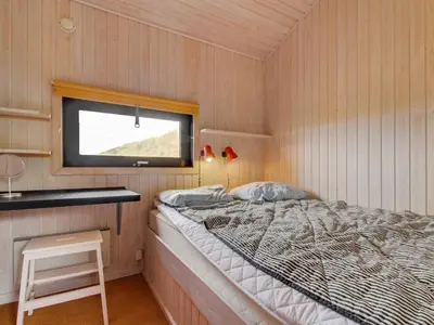 a small bedroom with a bed and a window at Holiday Home Riitta - 300m from the sea by Interhome in Løkken