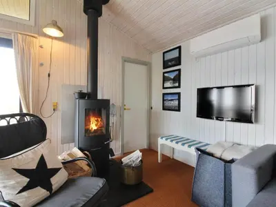 a living room with a fireplace and a tv at Holiday Home Riitta - 300m from the sea by Interhome in Løkken