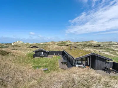 a black house on top of a grass covered hill at Holiday Home Ilmari - 190m from the sea by Interhome in Pandrup