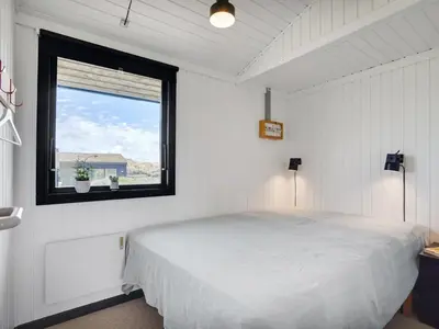 a bedroom with a white bed and a window at Holiday Home Ilmari - 190m from the sea by Interhome in Pandrup