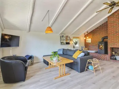 a living room with a couch and a table at Holiday Home Weland - 800m from the sea by Interhome in Løkken