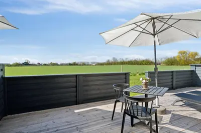 a patio with an umbrella and a table and chairs at Feriehuset Hygge ved Fjorden in Thyholm