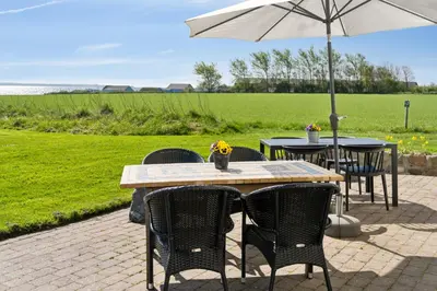 a table with chairs and an umbrella on a patio at Feriehuset Hygge ved Fjorden in Thyholm