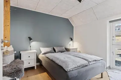 a bedroom with a bed and a white wall at Feriehuset Hygge ved Fjorden in Thyholm