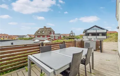 a patio with a table and chairs on a deck at Beautiful Home In Blokhus in Blokhus