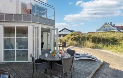a patio with a table and chairs on a deck at Beautiful Home In Blokhus in Blokhus