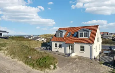 a white house with an orange roof on a beach at Beautiful Home In Blokhus in Blokhus