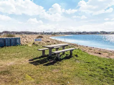 a picnic bench sitting on the grass near the water at 8 person holiday home in Højslev-By Traum in Højslev