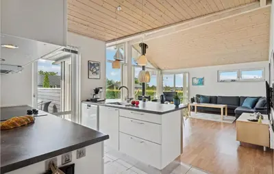 a kitchen with white cabinets and a living room at 3 Bedroom Lovely Home In Farsø in Farsø